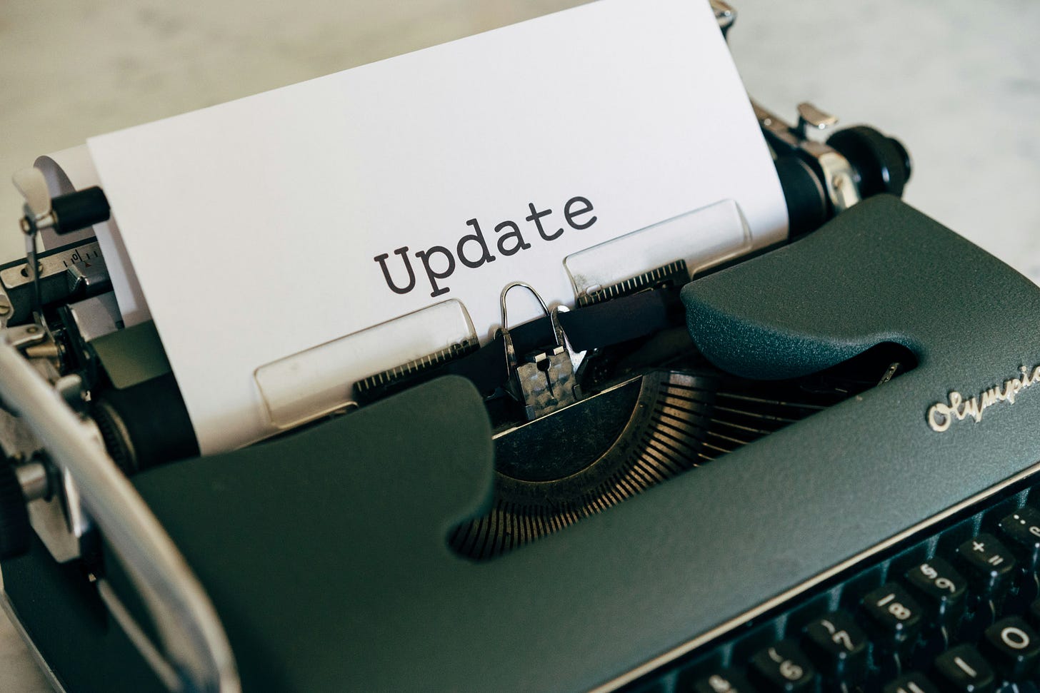 Vintage green typewriter with white paper showing the word "Update" typed in black text. Vintage green typewriter with white paper showing the word "Update" typed in black text.