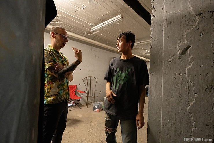 A director speaks to an actor in the basement set of a short film. A director speaks to an actor in the basement set of a short film.