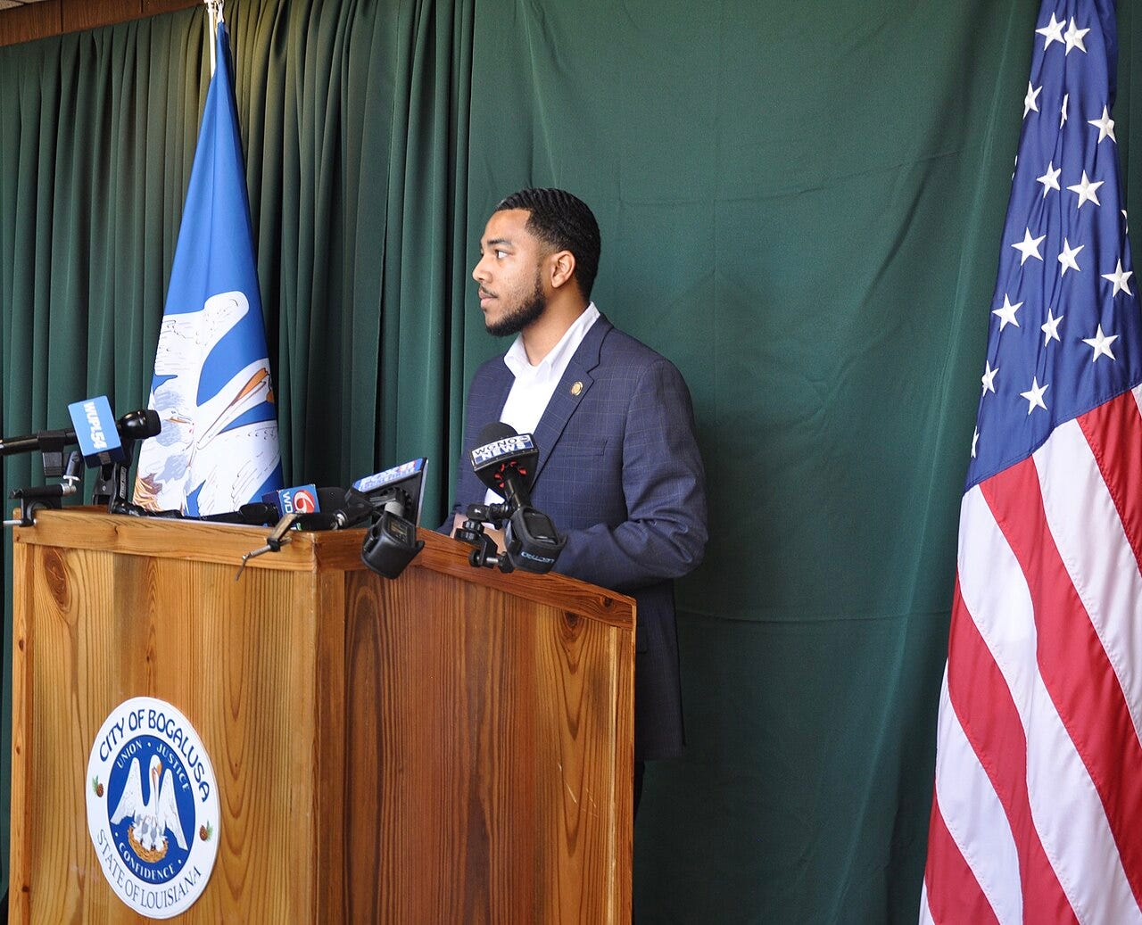 Photo: Timothy Holdiness / Wikimedia Commons (CC BY-SA 4.0) In this somber moment captured within the city hall, Mayor Tyrin Truong of Bogalusa addresses the media during a press conference. The conference was held in response to a tragic event where a 15-year-old student was fatally shot outside of a local h