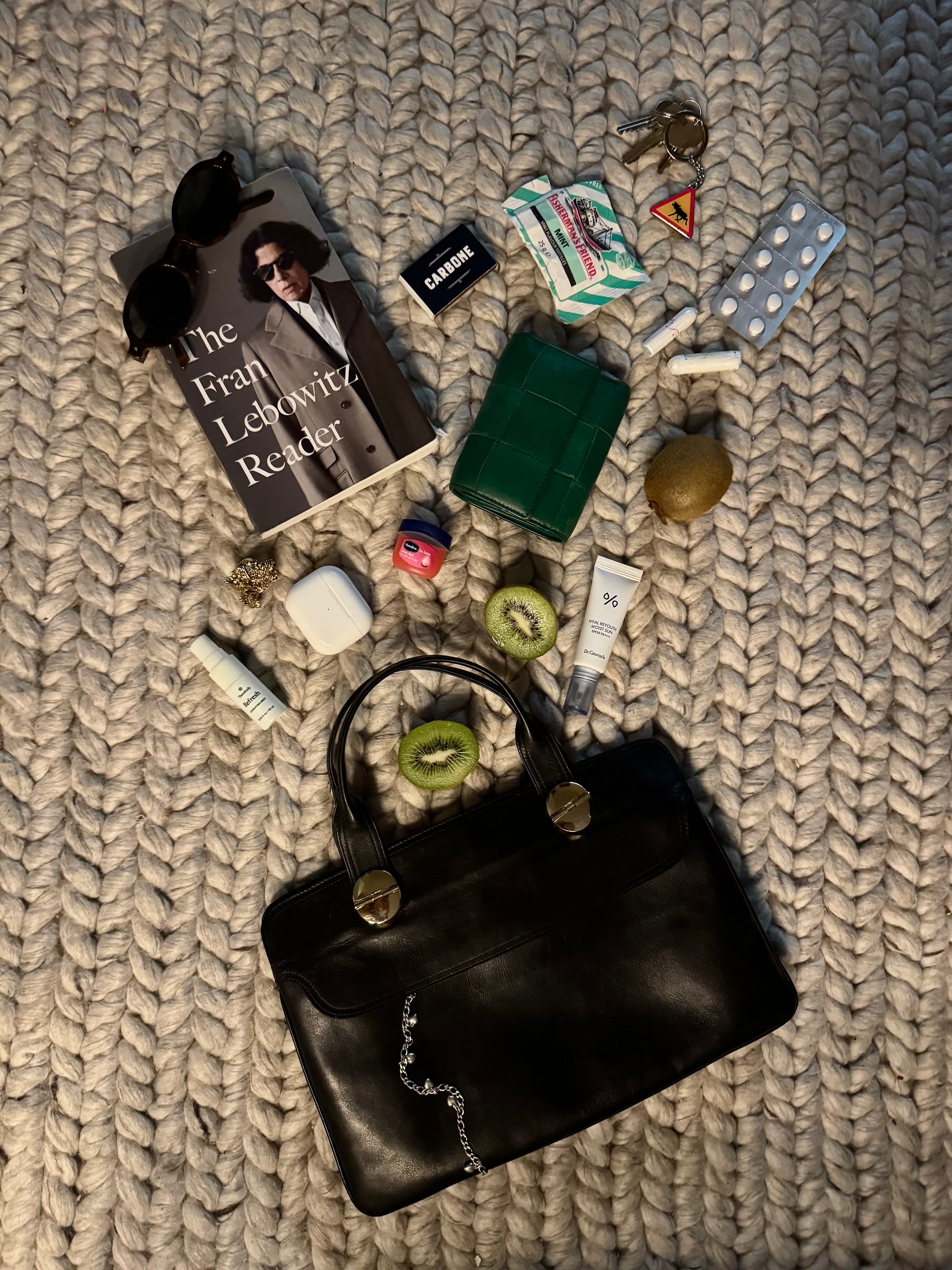 Aesthetic what's in my bag flatlay featuring tinted lip balm, sunglasses, and leather wallet styled on soft wool rug. Aesthetic what's in my bag flatlay featuring tinted lip balm, sunglasses, and leather wallet styled on soft wool rug.