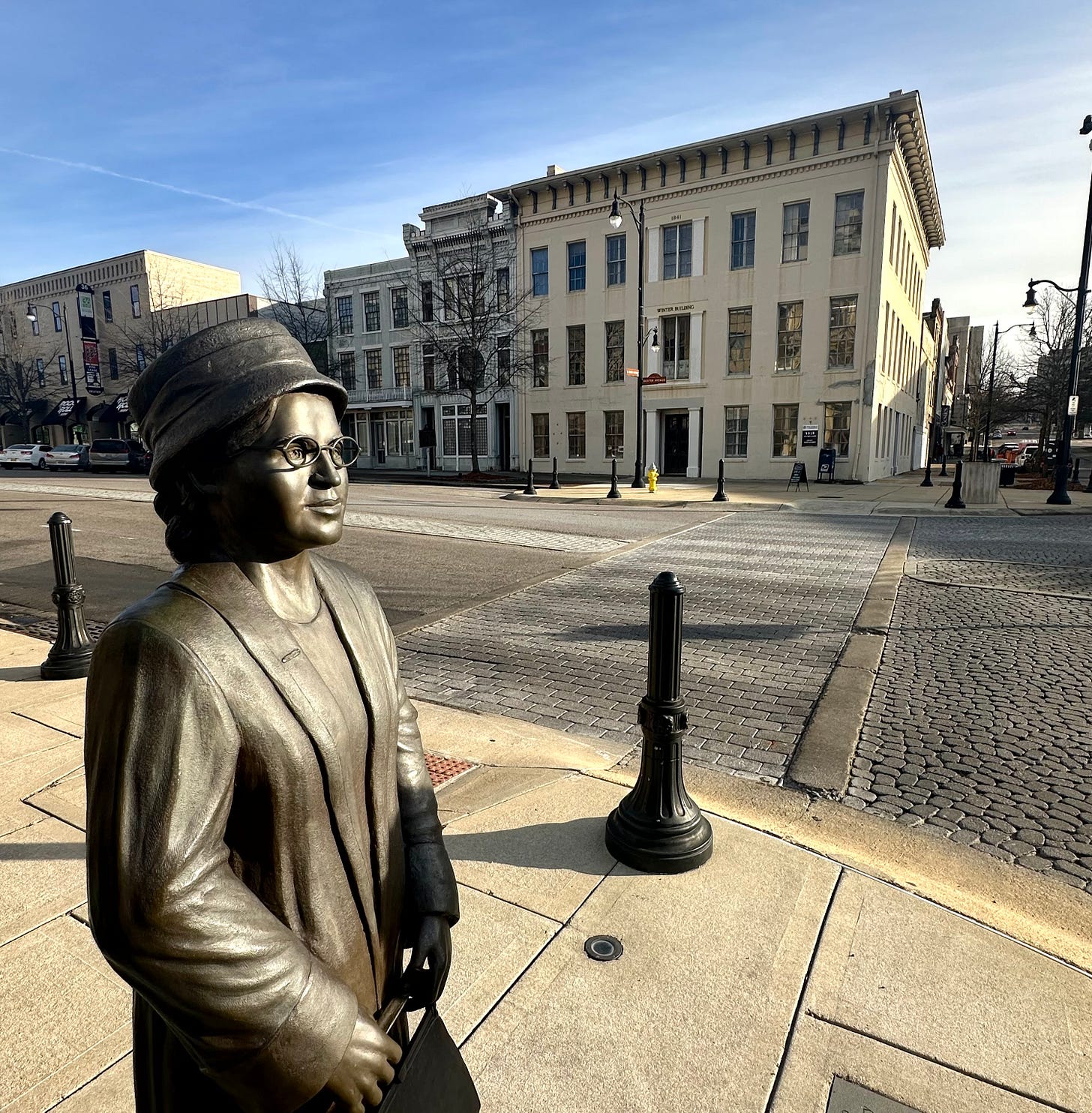 Rosa Parks statue on Dexter Avenue facing the Court Square Fountain, with the Winter Building in the background. Author photograph. February 1, 2024.Rosa Parks statue on Dexter Avenue facing the Court Square Fountain, with the Winter Building in the background Rosa Parks statue on Dexter Avenue facing the Court Square Fountain, with the Winter Building in the background. Author photograph. February 1, 2024.Rosa Parks statue on Dexter Avenue facing the Court Square Fountain, with the Winter Building in the background