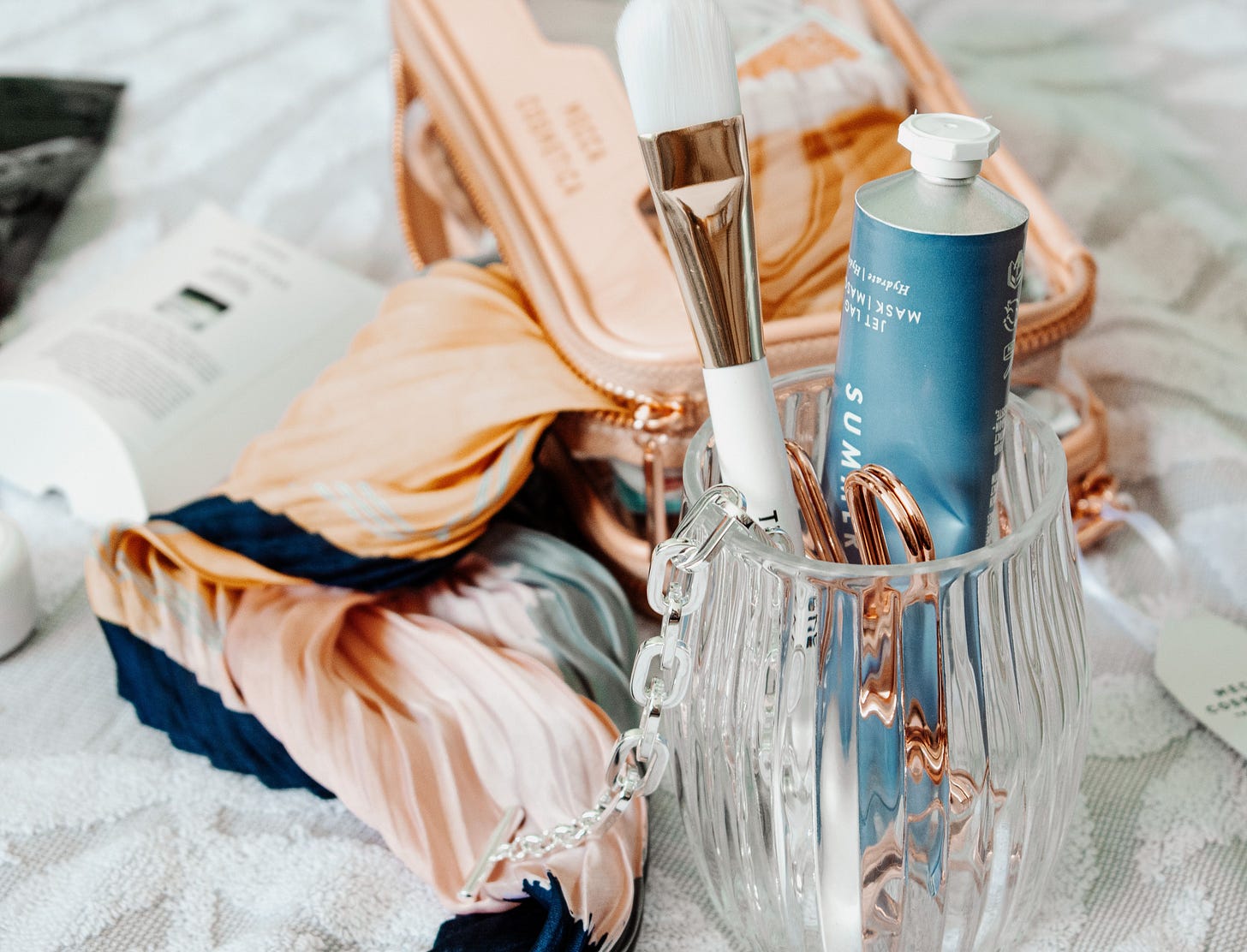 A curated makeup bag with everyday beauty essentials on a bed, featuring clean beauty products and neutral tones. A curated makeup bag with everyday beauty essentials on a bed, featuring clean beauty products and neutral tones.