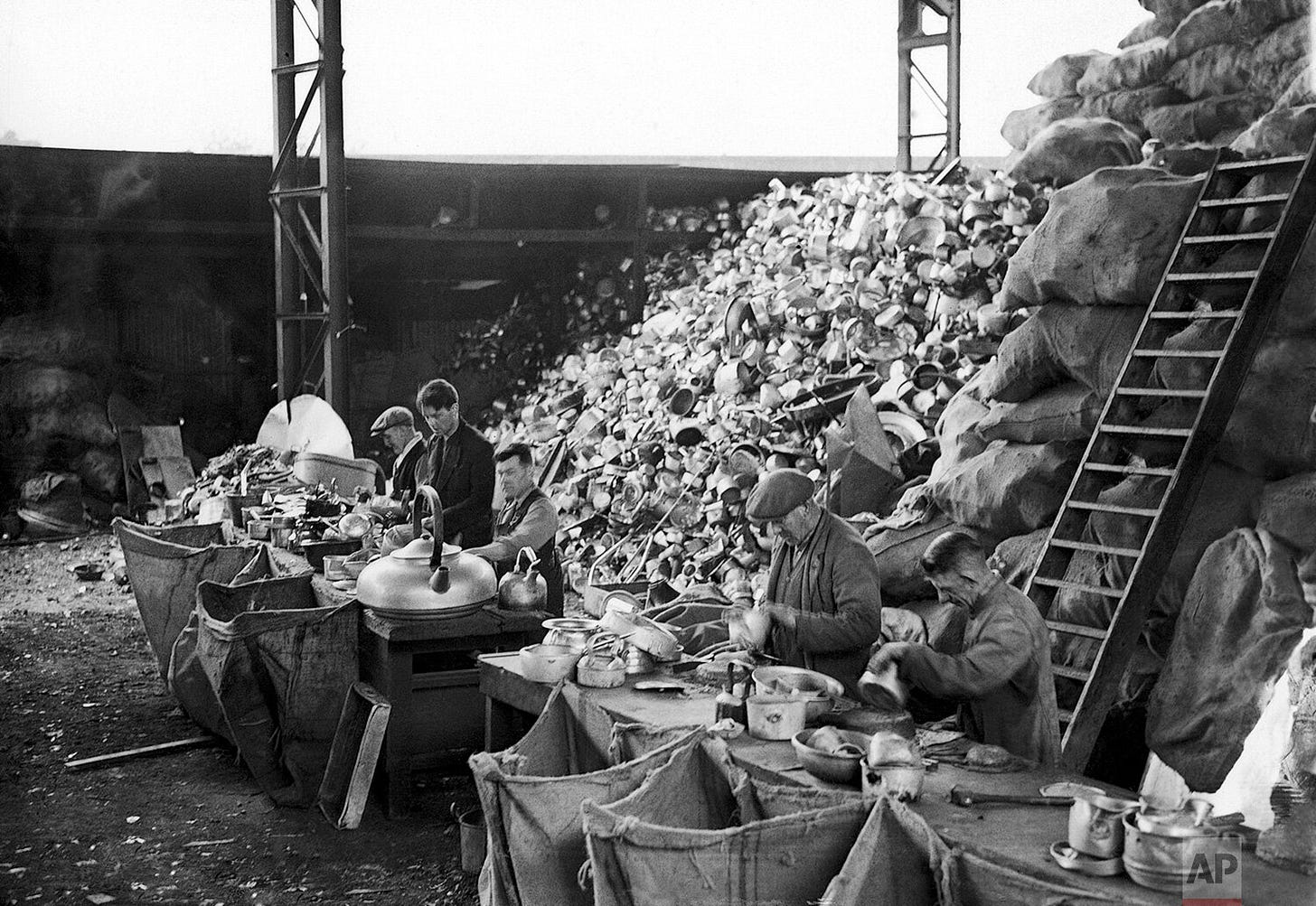 A massive pile of aluminum household items, including pans and kettles, at a sorting depot in England on Sept. 17, 1940. These vital materials were melted down to construct new fighter planes for the Royal Air Force, a testament to civilian contributions during the war.