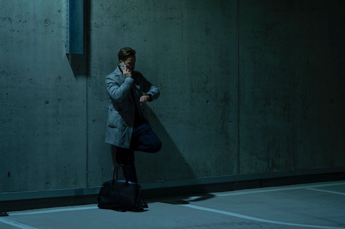 Man on Phone Call Leaning on Wall and Looking at his Watch