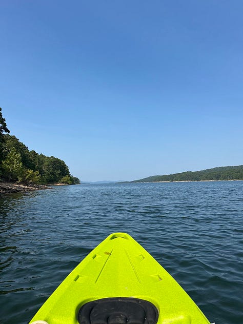 The left image shows a storage rack of eight blue, yellow, and gray kayaks for rent. The middle image shows a QR kayak checkout station, with a blue sign, a white sign letting Nicole know she can't sue Arkansas State Parks if she drowns, and a brown lockbox that holds oars and lifejackets. The final image is the sweet view of freedom: the front tip of a lime-green kayak is visible above a large lake of soft, deep blue waves.