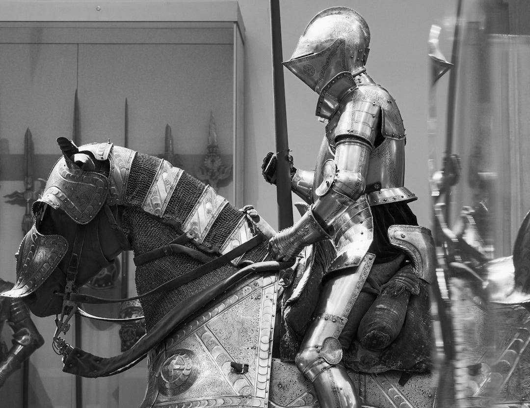 A knight in armor rides a metal horse.