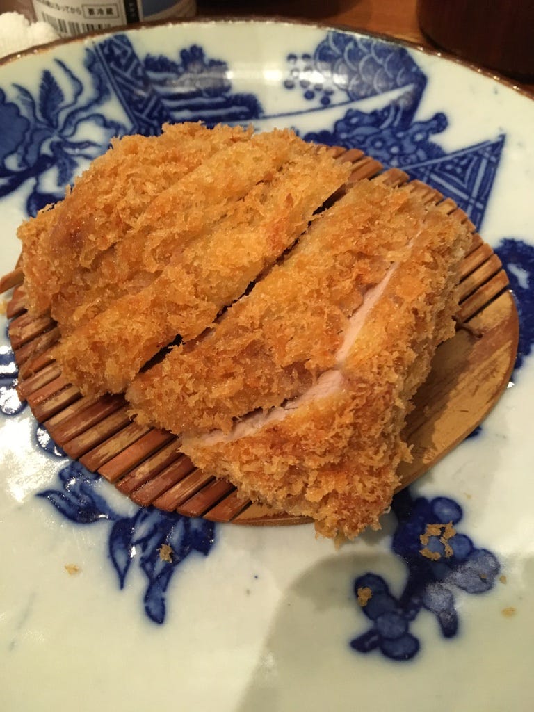 sliced tonkatsu on top of a bamboo disk on top of a porcelain plate sliced tonkatsu on top of a bamboo disk on top of a porcelain plate