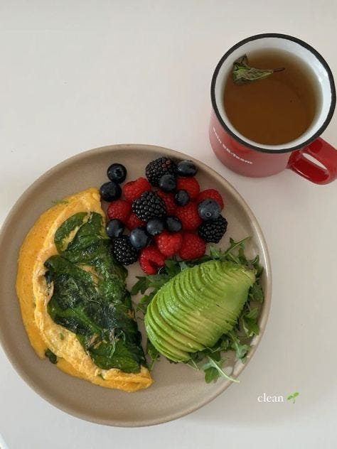 This may contain: an omelet with spinach, berries and avocado on a plate next to a cup of coffee This may contain: an omelet with spinach, berries and avocado on a plate next to a cup of coffee