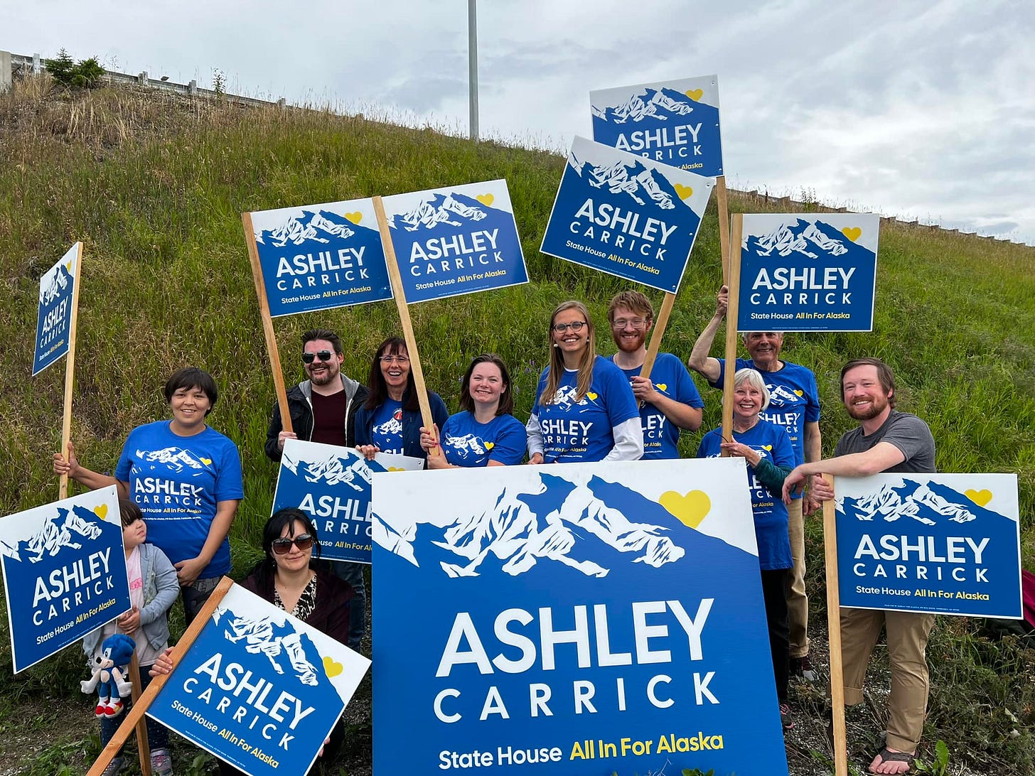 Ashley and supporters wave signs at the Justa Store intersection.