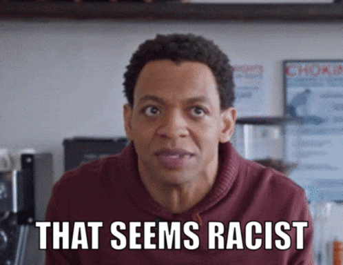 A Black person in a red shirt is talking to a white person. He says, that seems rascist, and she responds Because it is. 