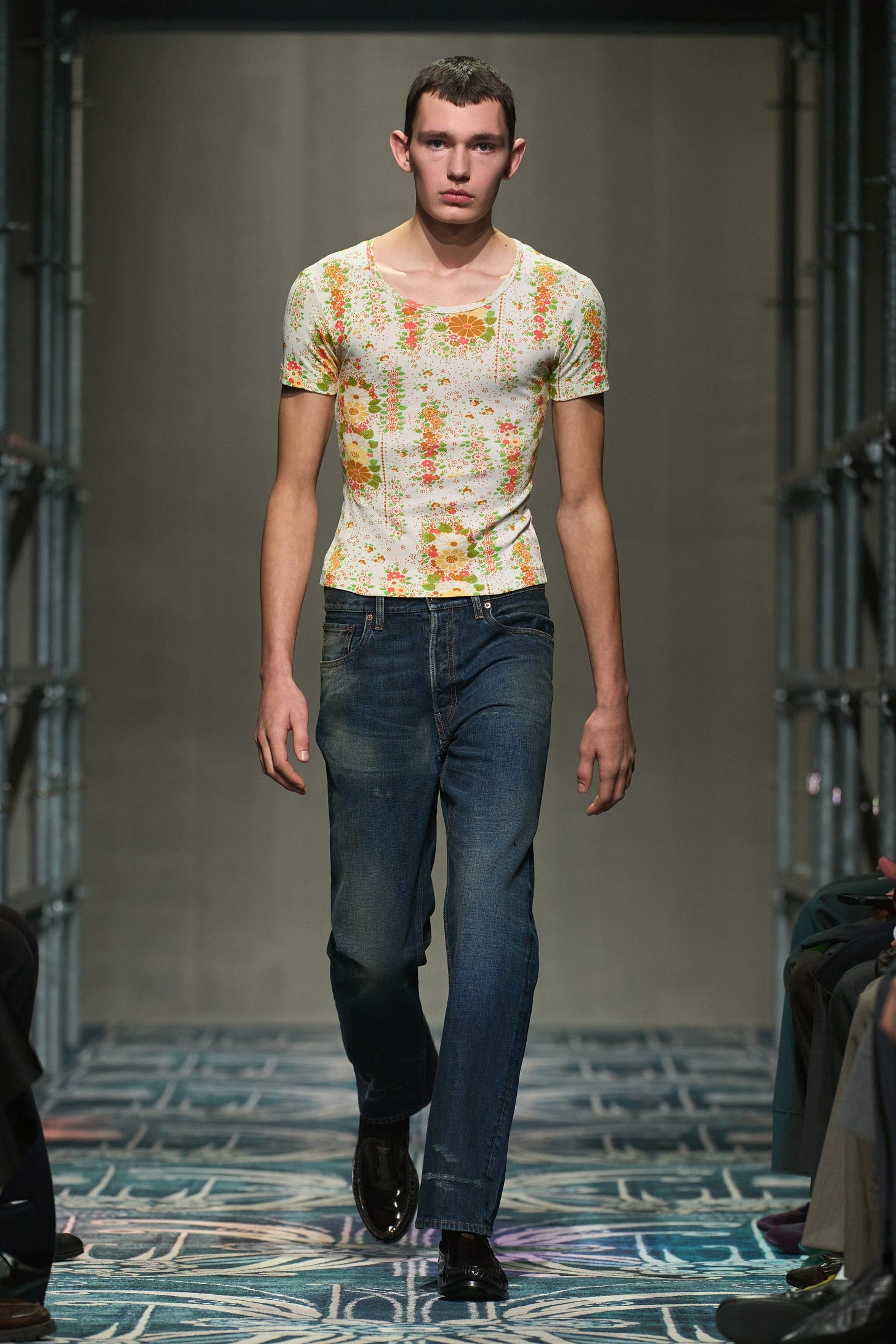 A model walks the runway wearing a shrunken yee with a vintage floral print and jeans.