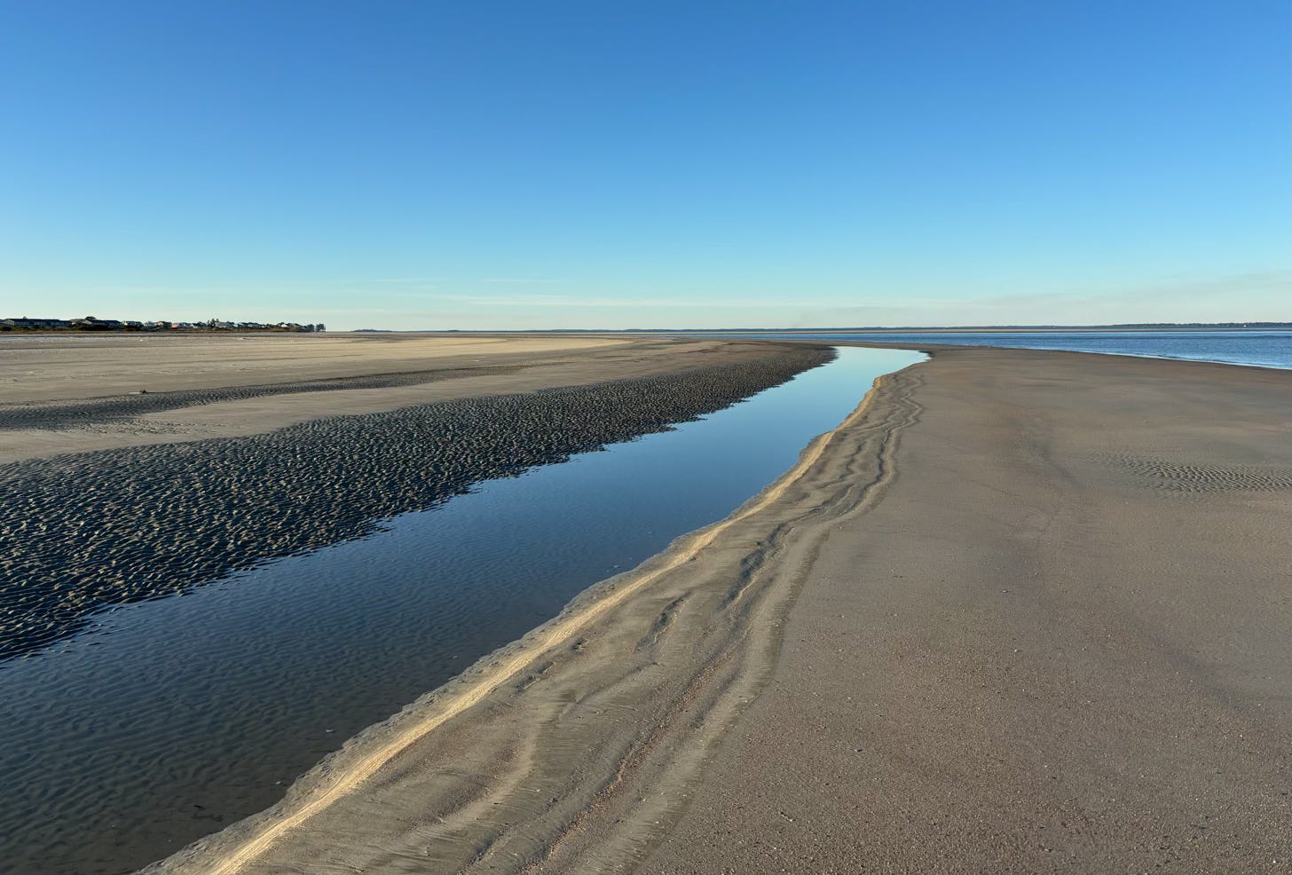 ocean shoreline with tide pool reflecting bright blue sky