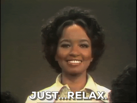 A Black woman in a yellow shirt is saying "Just...relax."