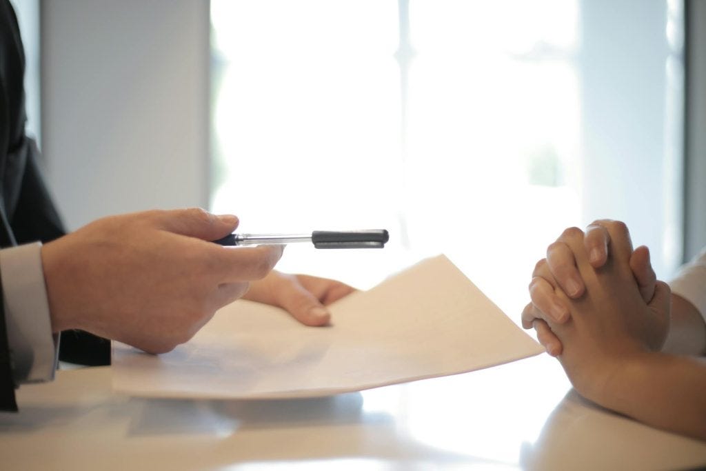 close up of two people exchanging a written contract