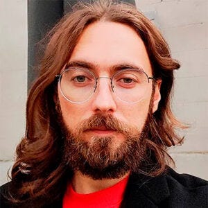 Homem de cabelos compridos e barba, de olhos claros, usando óculos Homem de cabelos compridos e barba, de olhos claros, usando óculos