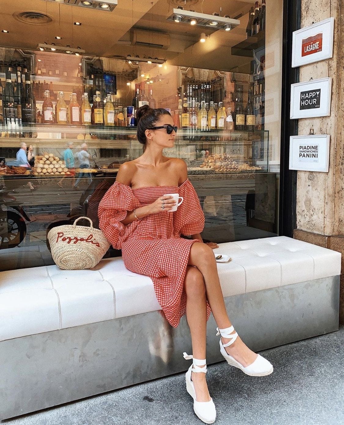 mujer con vestido ligero, alpargatas y bolso estructurado perfecto para entretiempo tomando un café