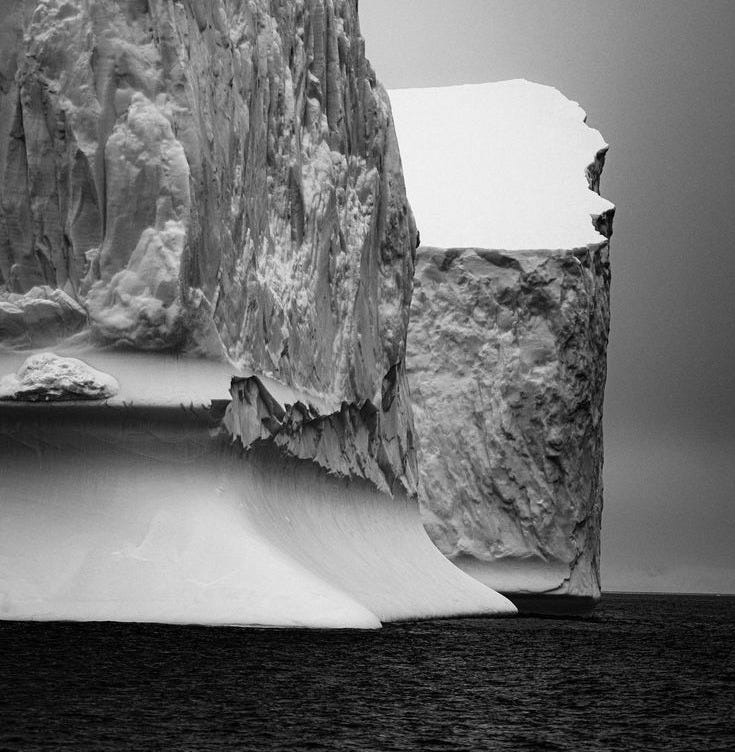 This may contain: an iceberg in the middle of the ocean with snow on it's sides