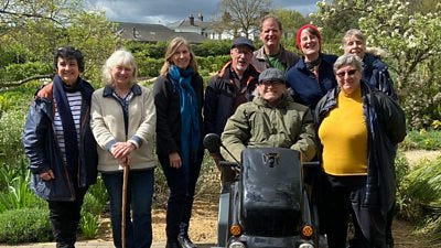 A group of people in a garden in the sunshine. They all smile to the camera. A group of people in a garden in the sunshine. They all smile to the camera.