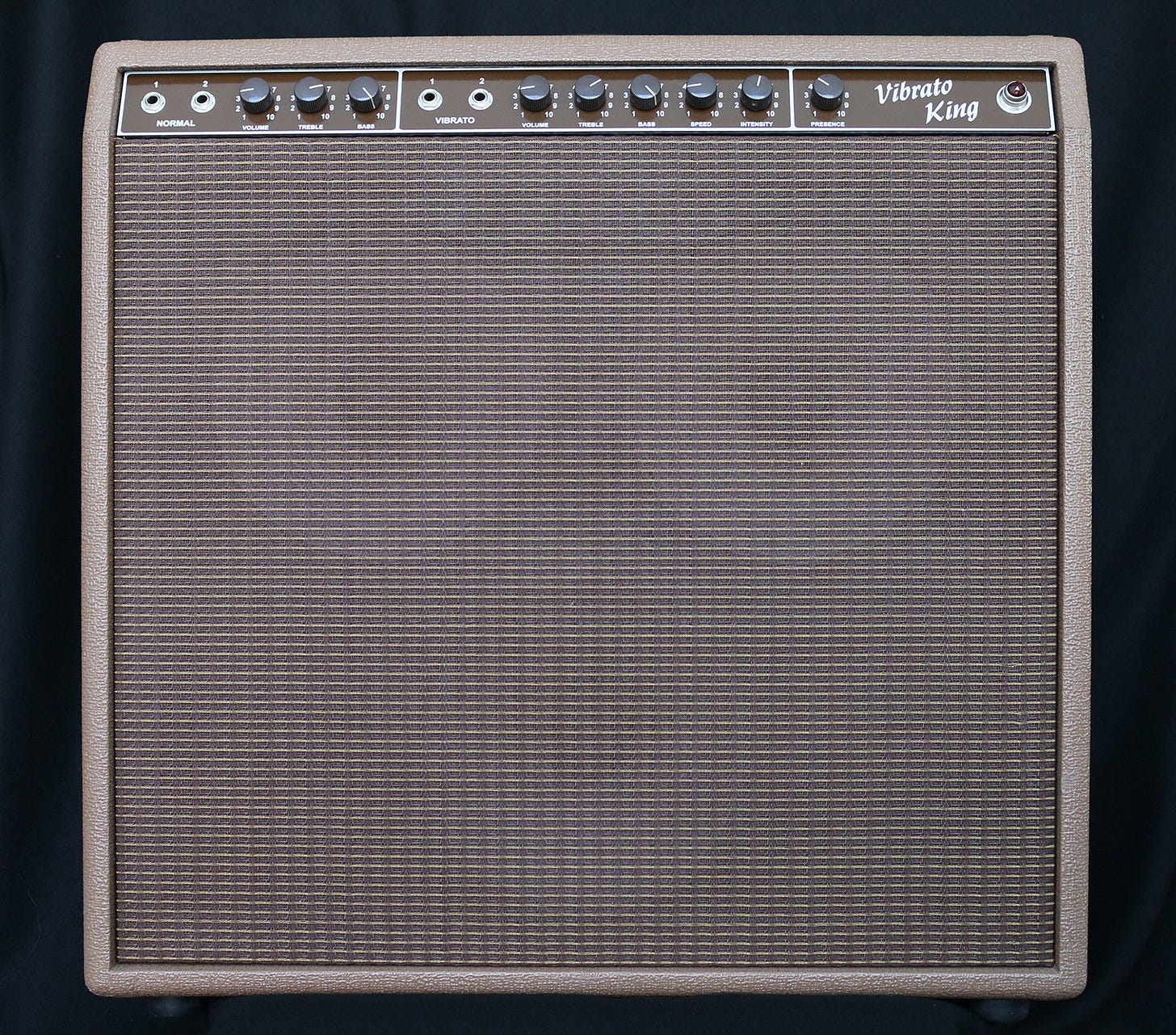 A brown Vibrato King guitar amp with knobs and mesh front