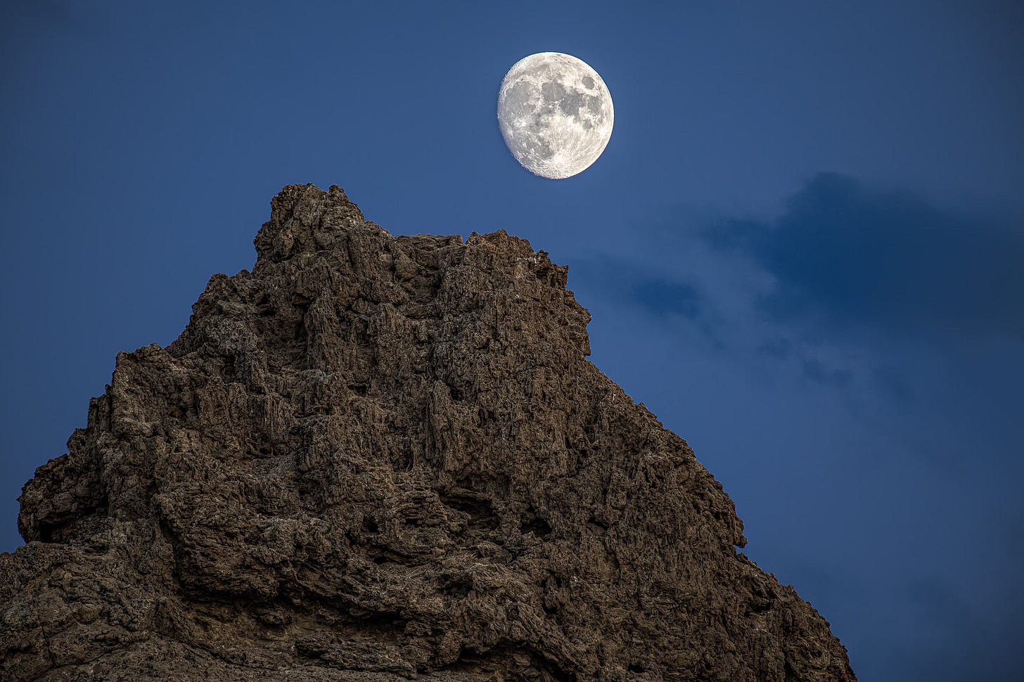 Nearly full moon above a Trona Pinnacle rock outcrop.