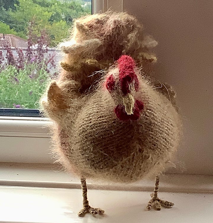 A knitted checking and a knitted rabbit become acquainted, the rabbit is sitting on the chicken and then the chicken is stood up.