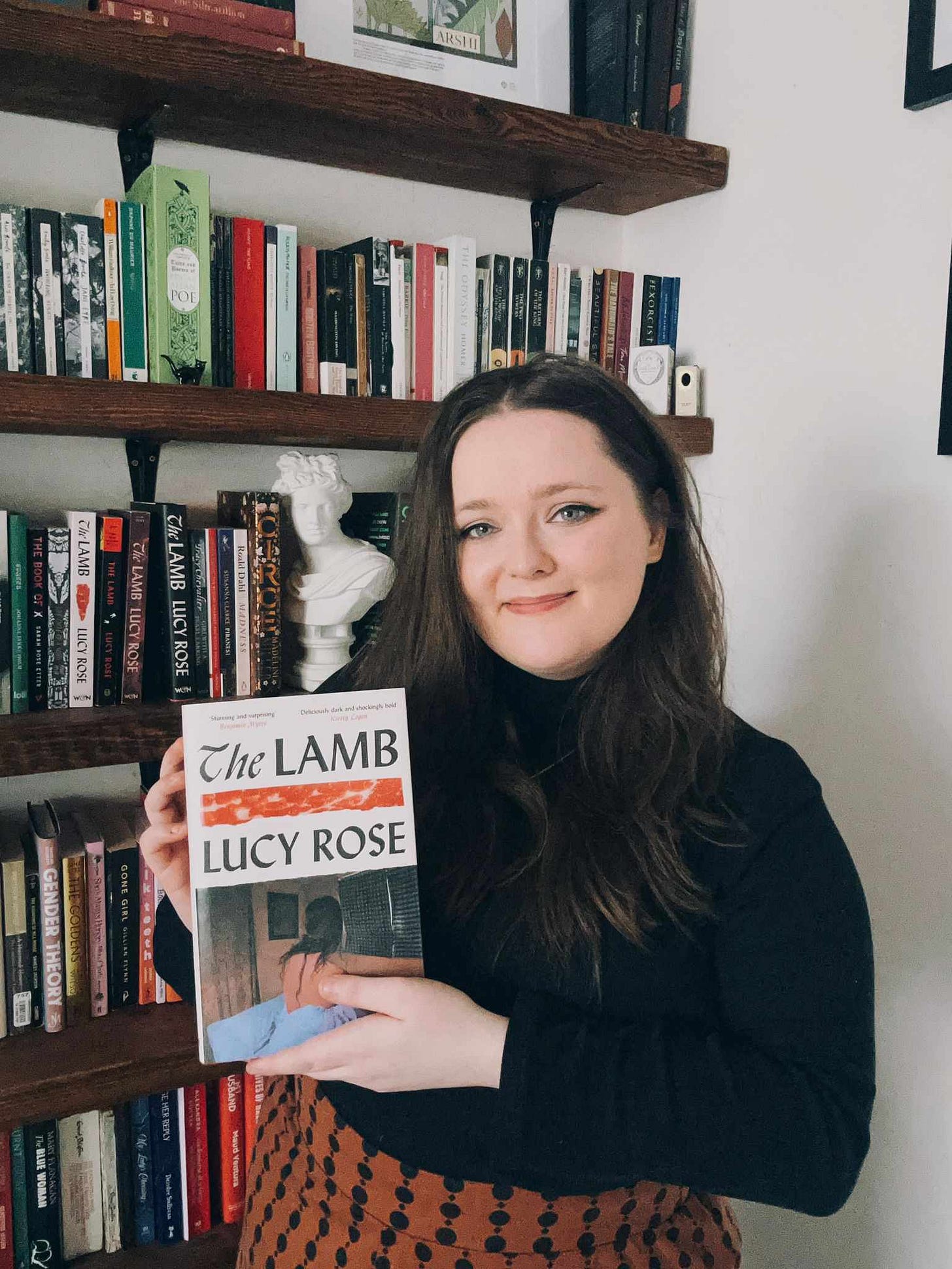 girl in a black jumper (she’s done her hair and make up for once). she’s holding up her debut novel and she’s very proud. 
