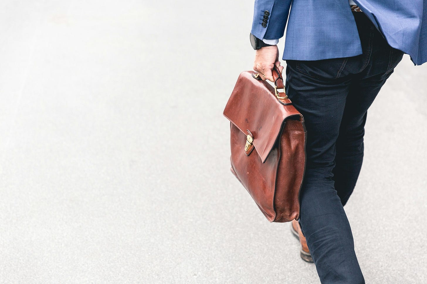 person walking holding brown leather bag person walking holding brown leather bag