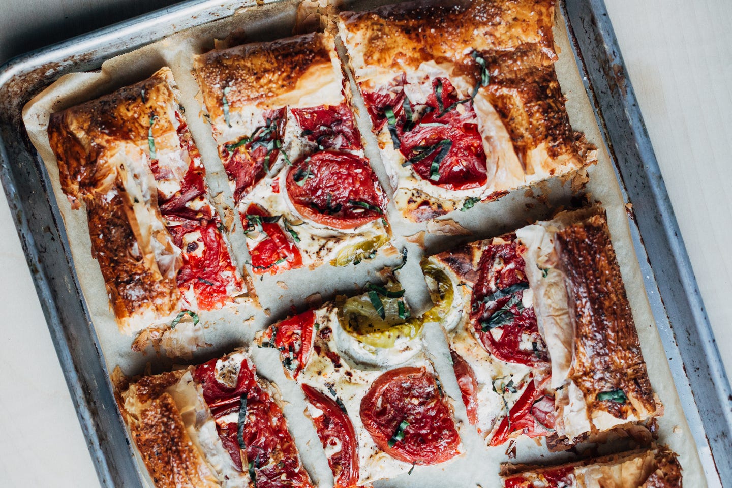 A tomato tart, sliced in the baking sheet. 