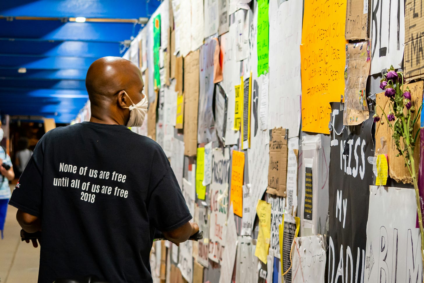 Man wearing a shirt that says "none of us are free until all of us are free"