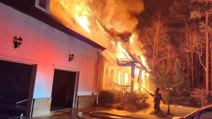 A firefighter attempts to put out a fire at the home of the parents of NASCAR star Denny Hamlin.