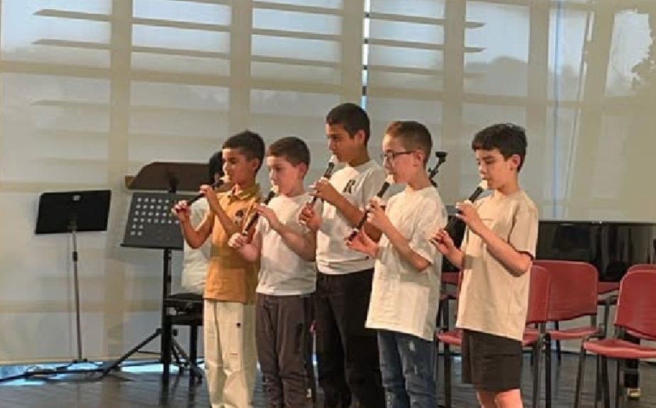 Four elementary school boys playing the recorder at their spring end-of-term recital. Accompanist seen in background. Four elementary school boys playing the recorder at their spring end-of-term recital. Accompanist seen in background.