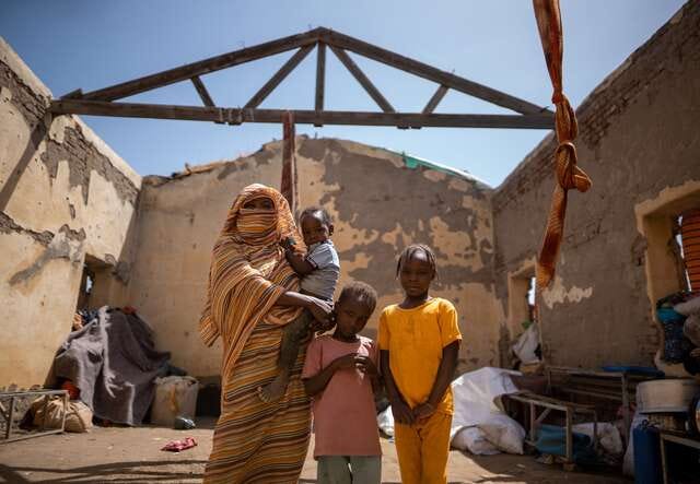Altuma stands in her temporary house with her three children. Altuma stands in her temporary house with her three children.