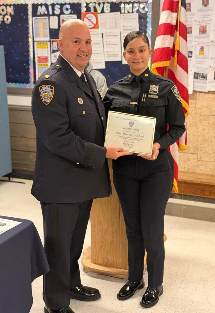 A male police officer presenting a certificate to Police Officer Rebecca De Paula.