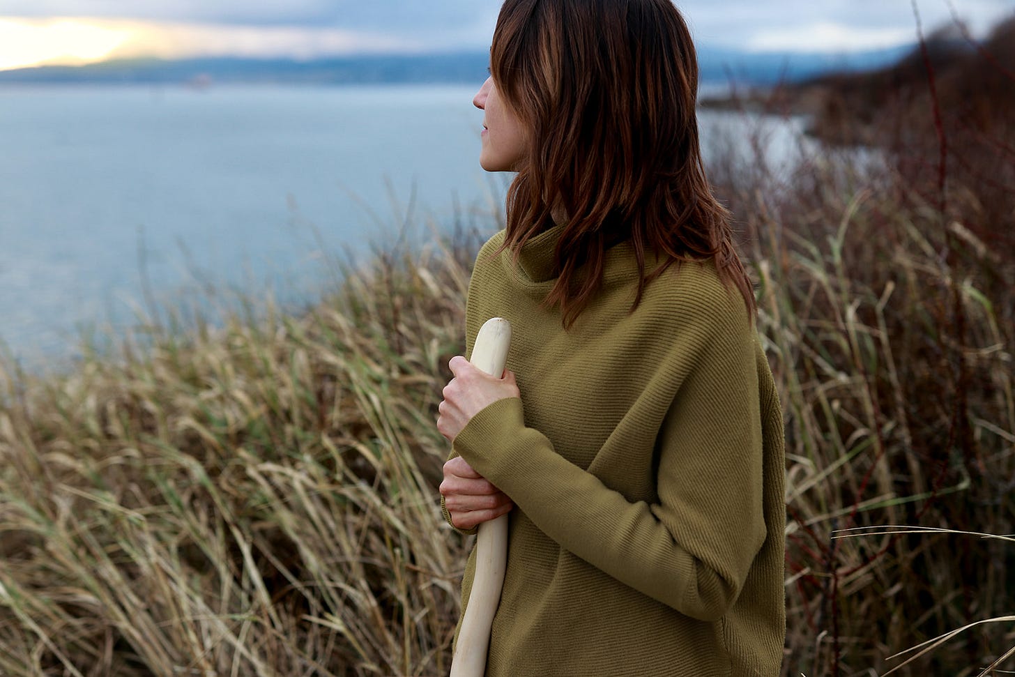 Rayann looks out at ocean holding a staff