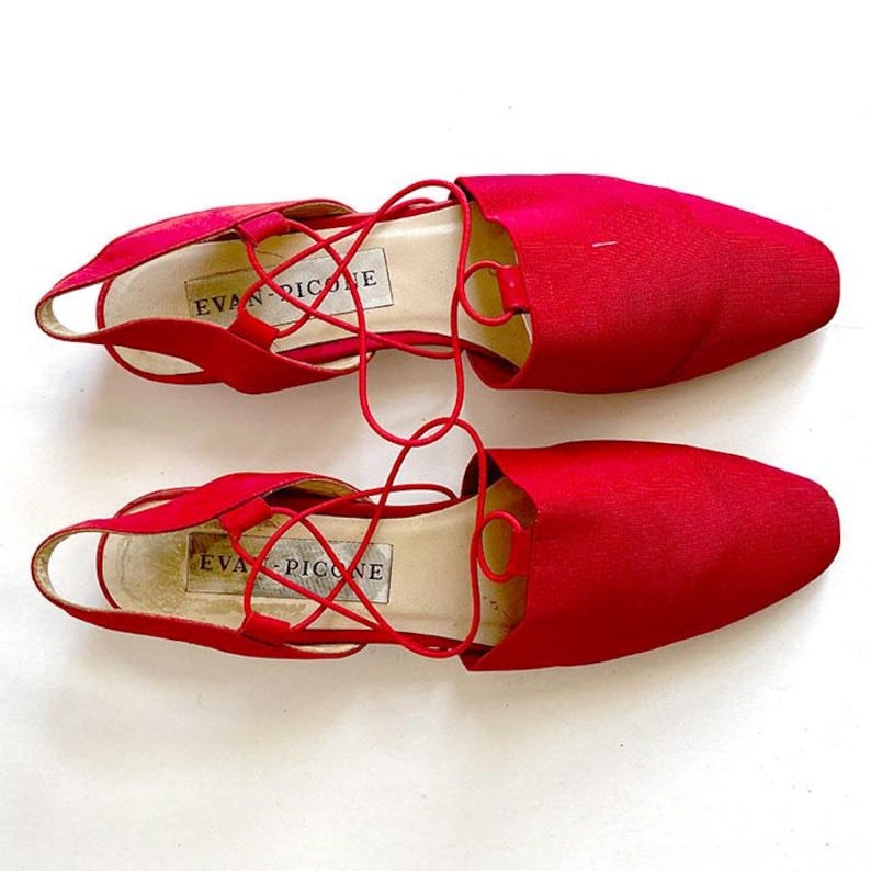 May include: A pair of red satin shoes with lace-up detailing. The shoes have a pointed toe and a low heel. The brand name 'Evan-Picone' is printed on the insole of each shoe.