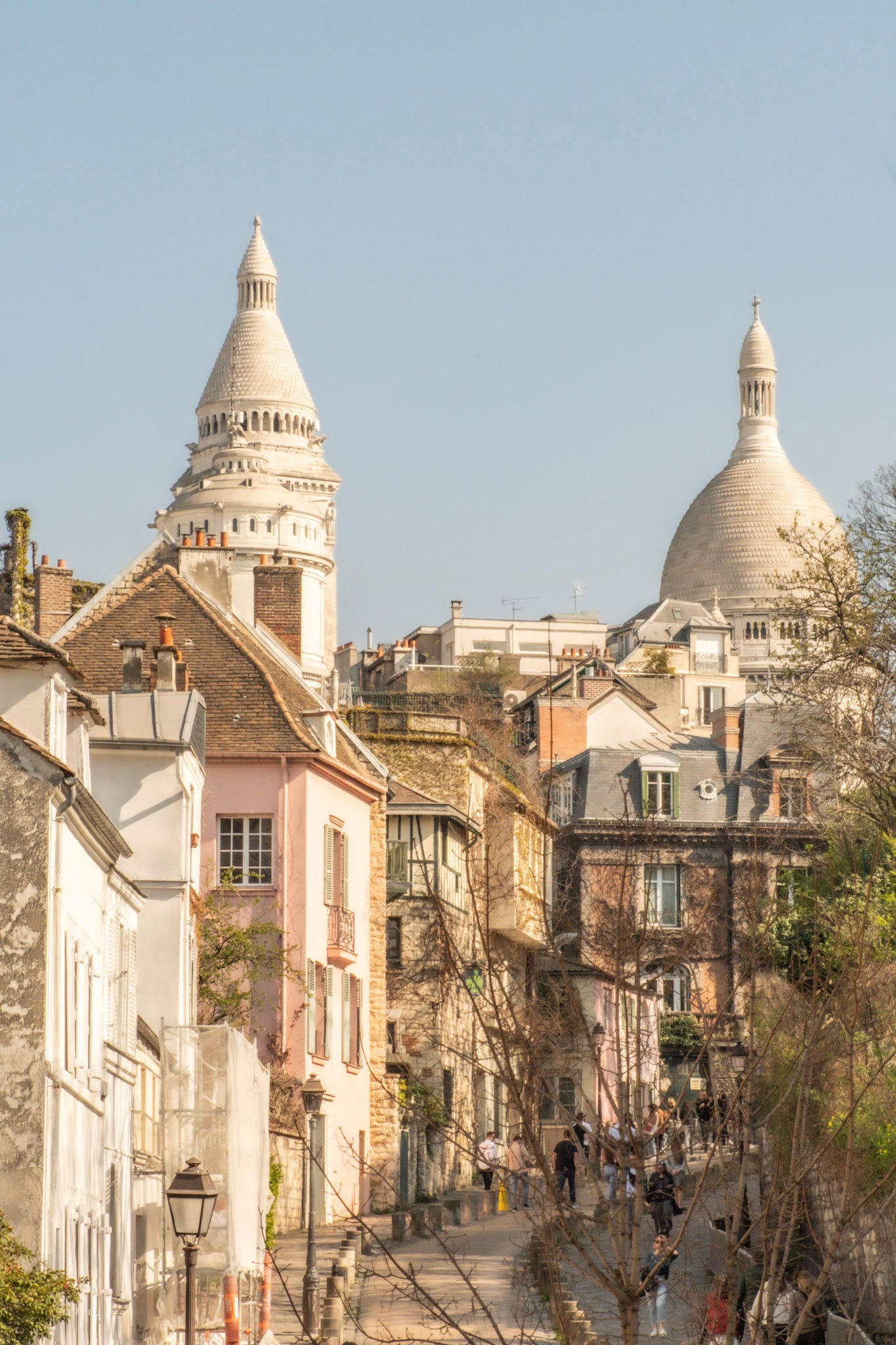 The domes of Sacré-Cœur rise above the rooftops of Montmartre, viewed from Rue du Mont-Cenis after walking beyond Rue de l'Abreuvoir.