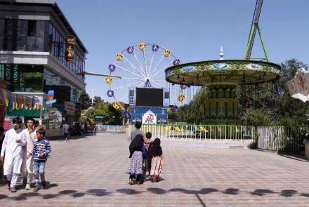 A group of people walking in front of a building with a ferris wheel

Description automatically generated with low confidence