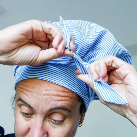 women making a knot in the straps of a hair bonnet on the front women making a knot in the straps of a hair bonnet on the front