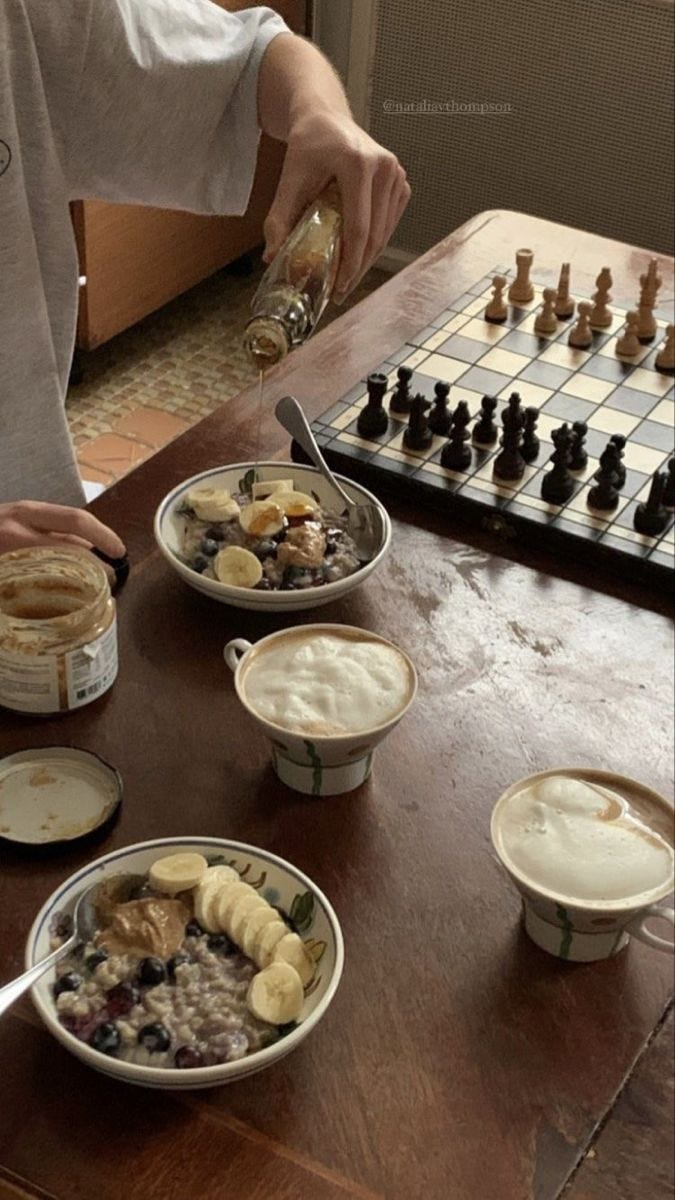 This may contain: a man sitting at a table with several bowls of food on it, and chess in the background