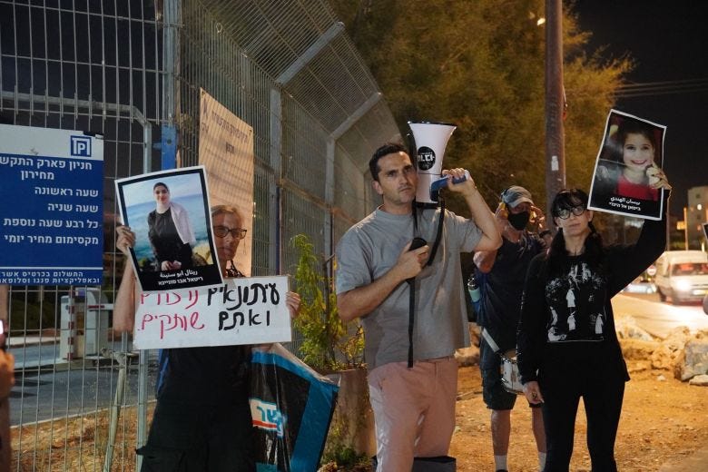 Israeli filmmaker Roy Cohen stands holding a megaphone at a protest. 