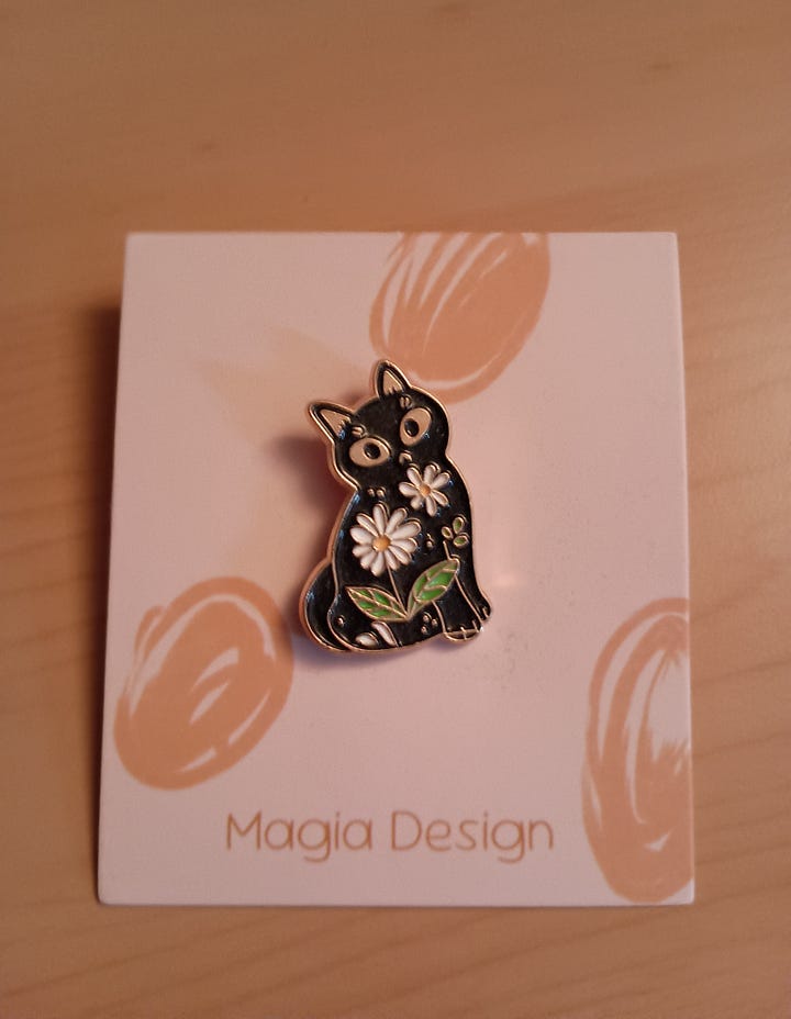 enamel cat with flowers and a butterfly decorated with stars and moons