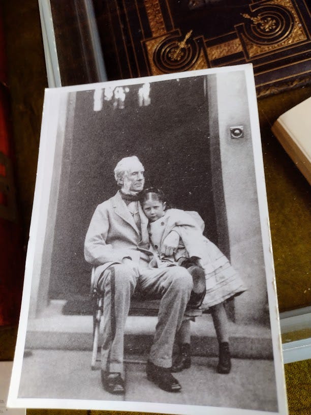 Hands holding certificate in front of fireplace, and photo of old man with little girl leaning against him