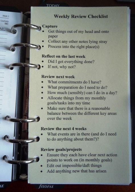 This may contain: an open spiral notebook with some writing on the page and a list attached to it that says weekly review checklist