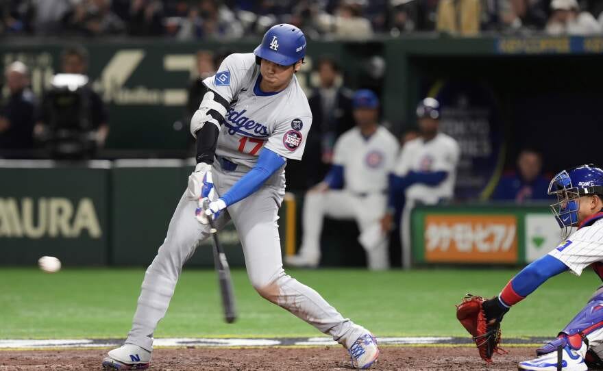 Los Angeles Dodgers' Shohei Ohtani, left, connects for a double as Chicago Cubs' Miguel Amaya, right, looks on in the ninth inning of an MLB Japan Series baseball game in Tokyo, Japan, Tuesday, March 18, 2025. (AP Photo/Eugene Hoshiko)