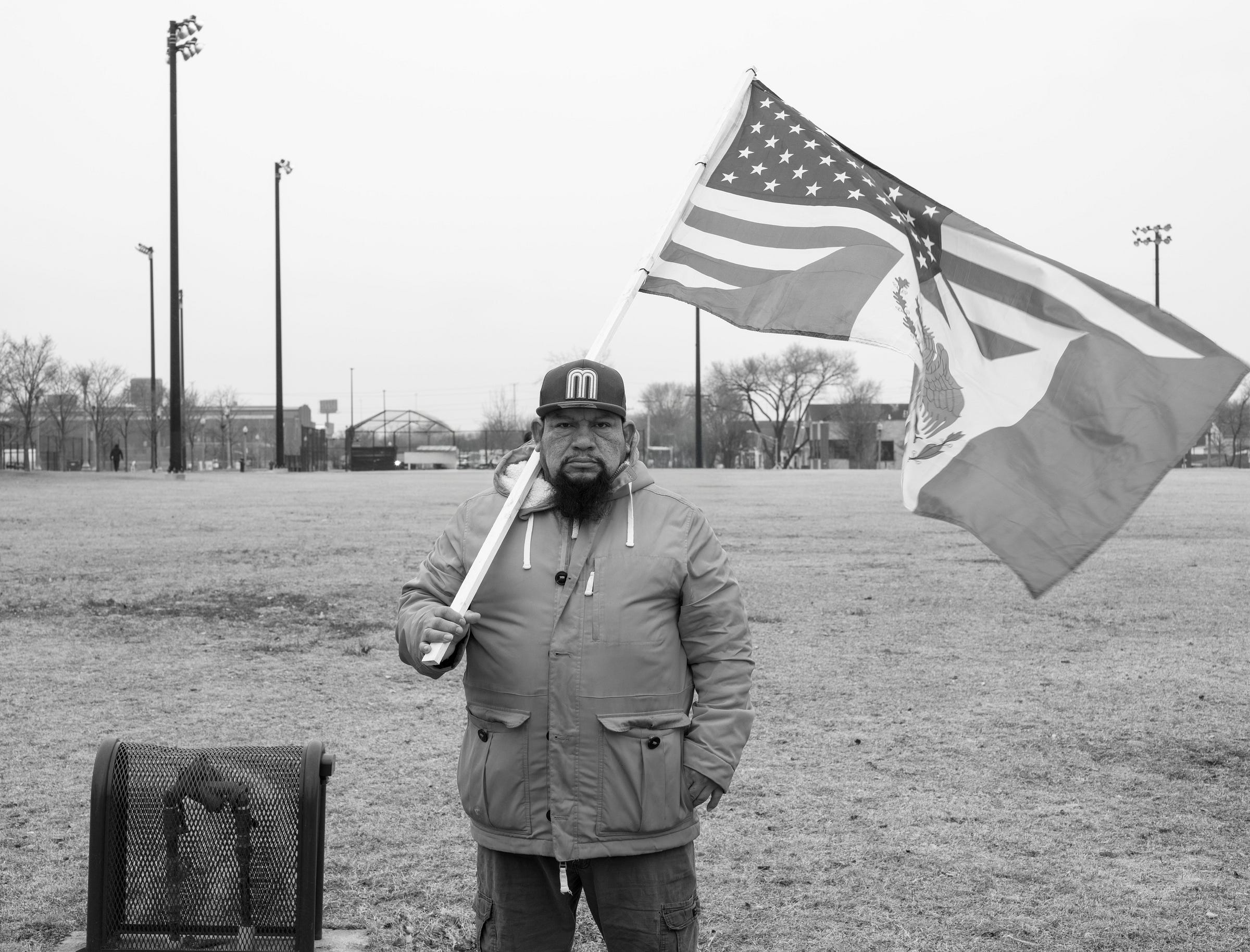 Black-and-white photo of a man staring into the camera carrying a flag.