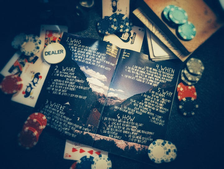 A zine with a cow skull and playing cards on the cover, artfully placed in a pile of poker chips and playing cards. Inside is a page of spooky tables with questions about your character.