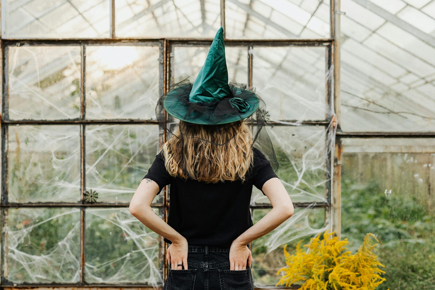 Woman wearing a witches hat standing in a greenhouse