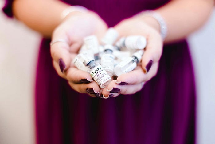 A woman in plum with her hands full of vials A woman in plum with her hands full of vials