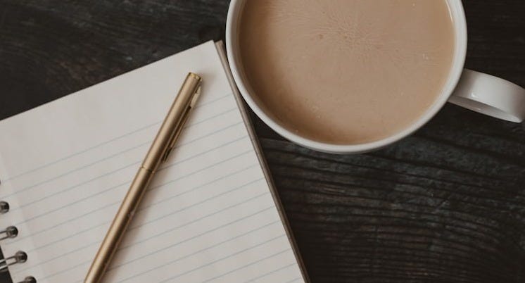 a cup of coffee and a pen on a table