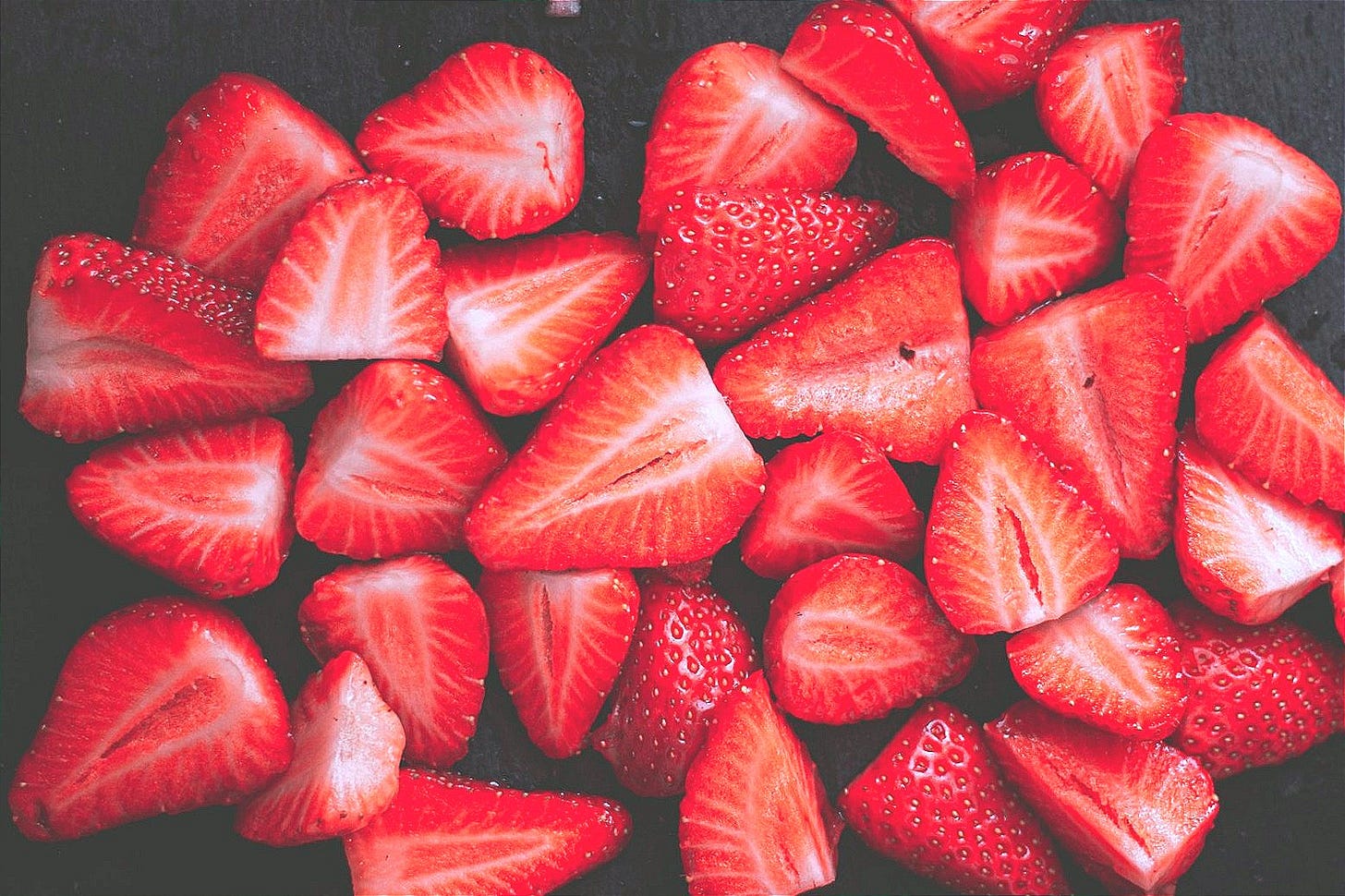 sliced strawberries on black surface